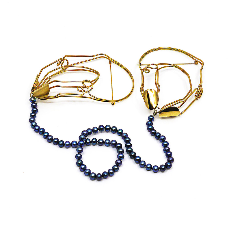 two hand shaped 18 carat gold plated brass wire brooches joined by a string of blue pearls