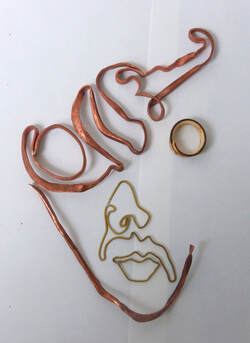 shaped copper and brass wire with metal ring laid flat to resemble a face